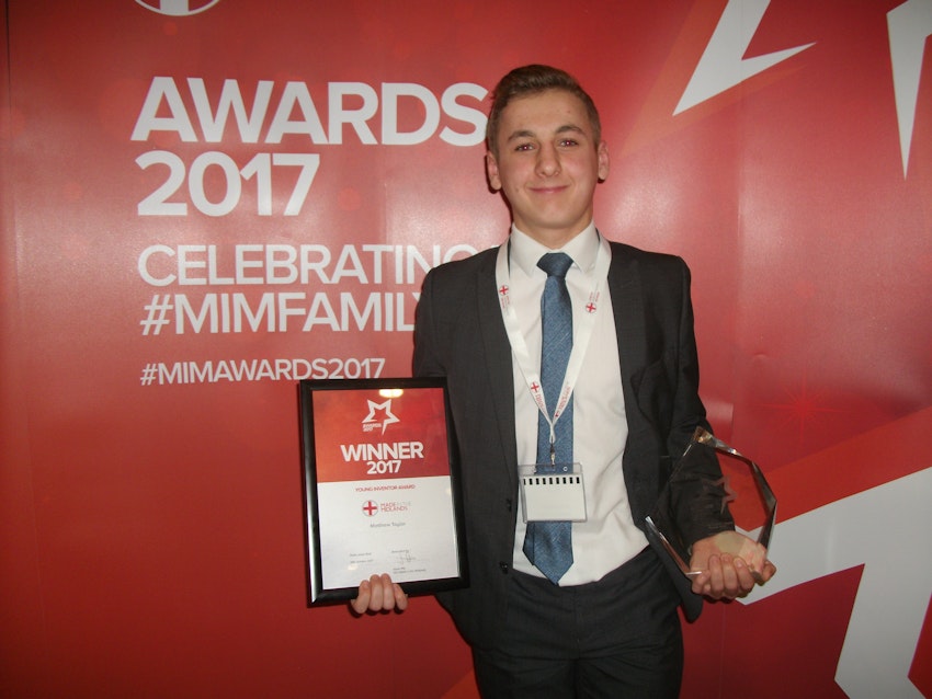 Person smiling holding a certificate and a trophy